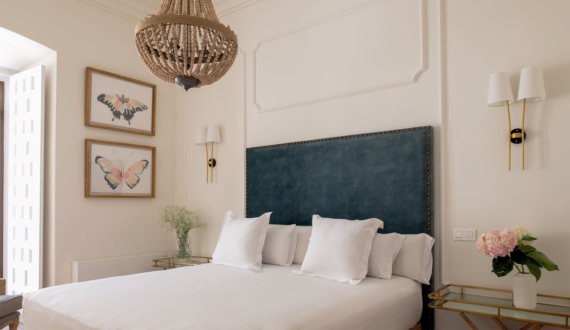 a bedroom with a blue headboard and two framed butterflies on the wall