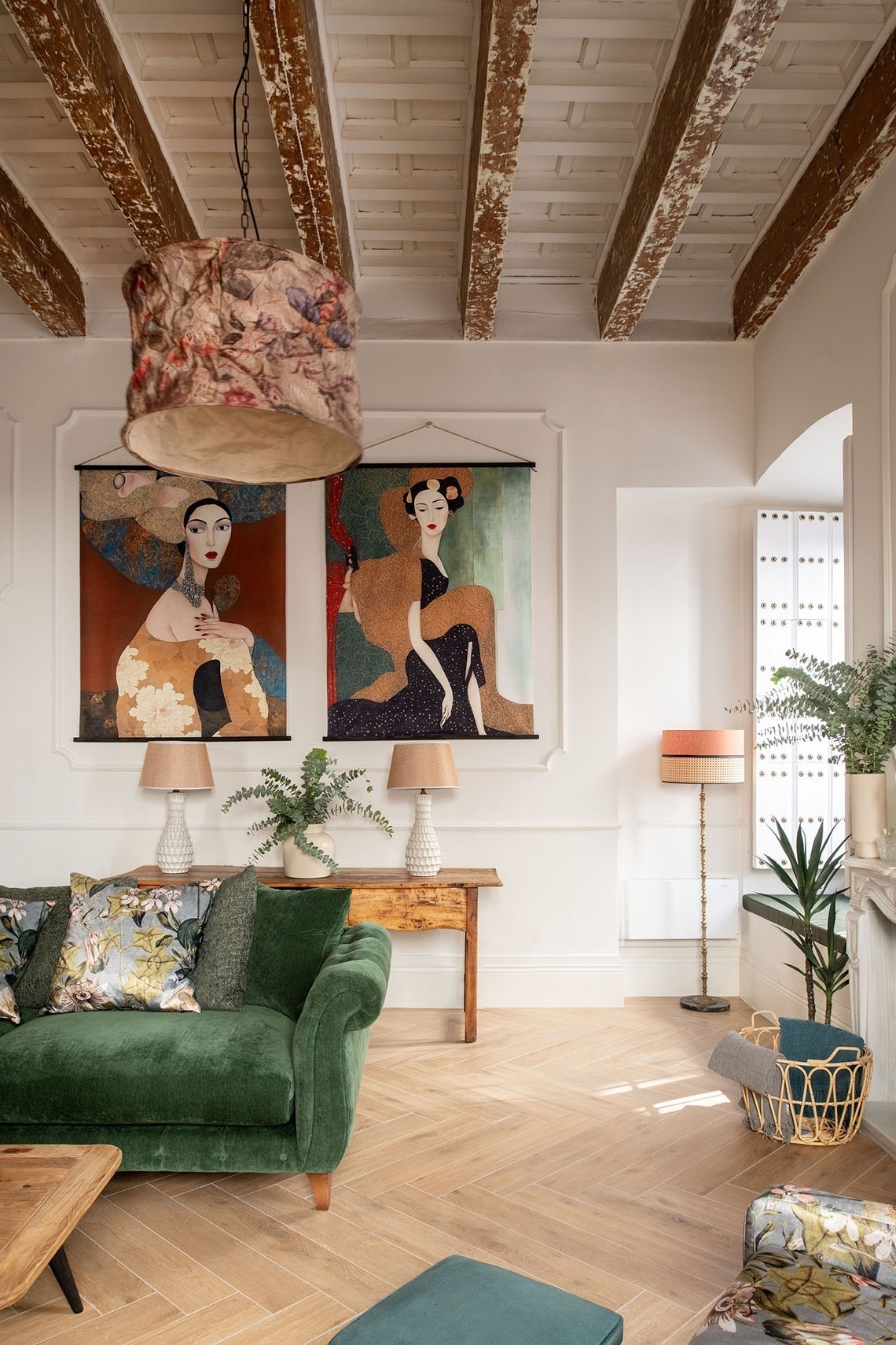 a living room with a green couch and two paintings on the wall