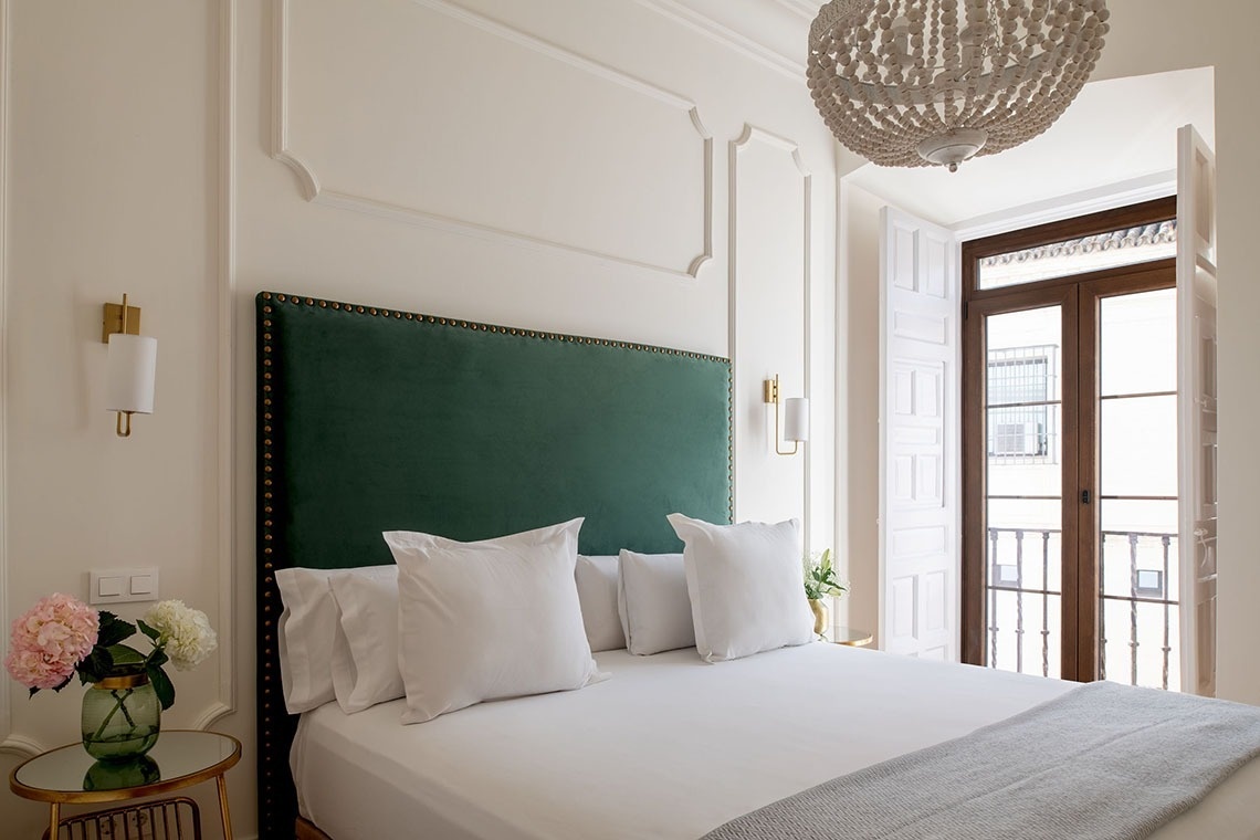 a bedroom with a green headboard and white pillows