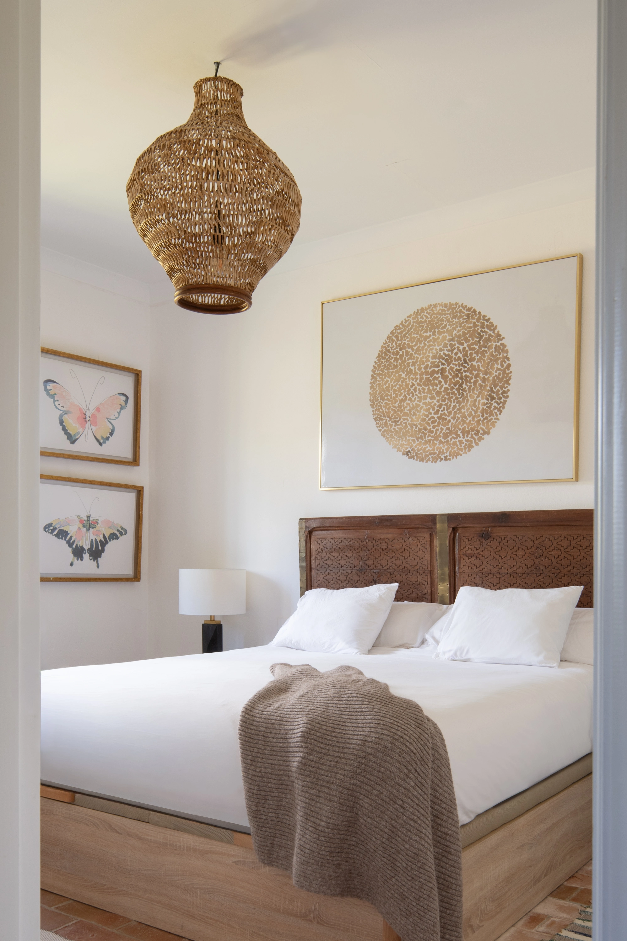 Luxury bedroom Epoca Suites: Corporativa with woven pendant, butterfly art, and upholstered headboard.