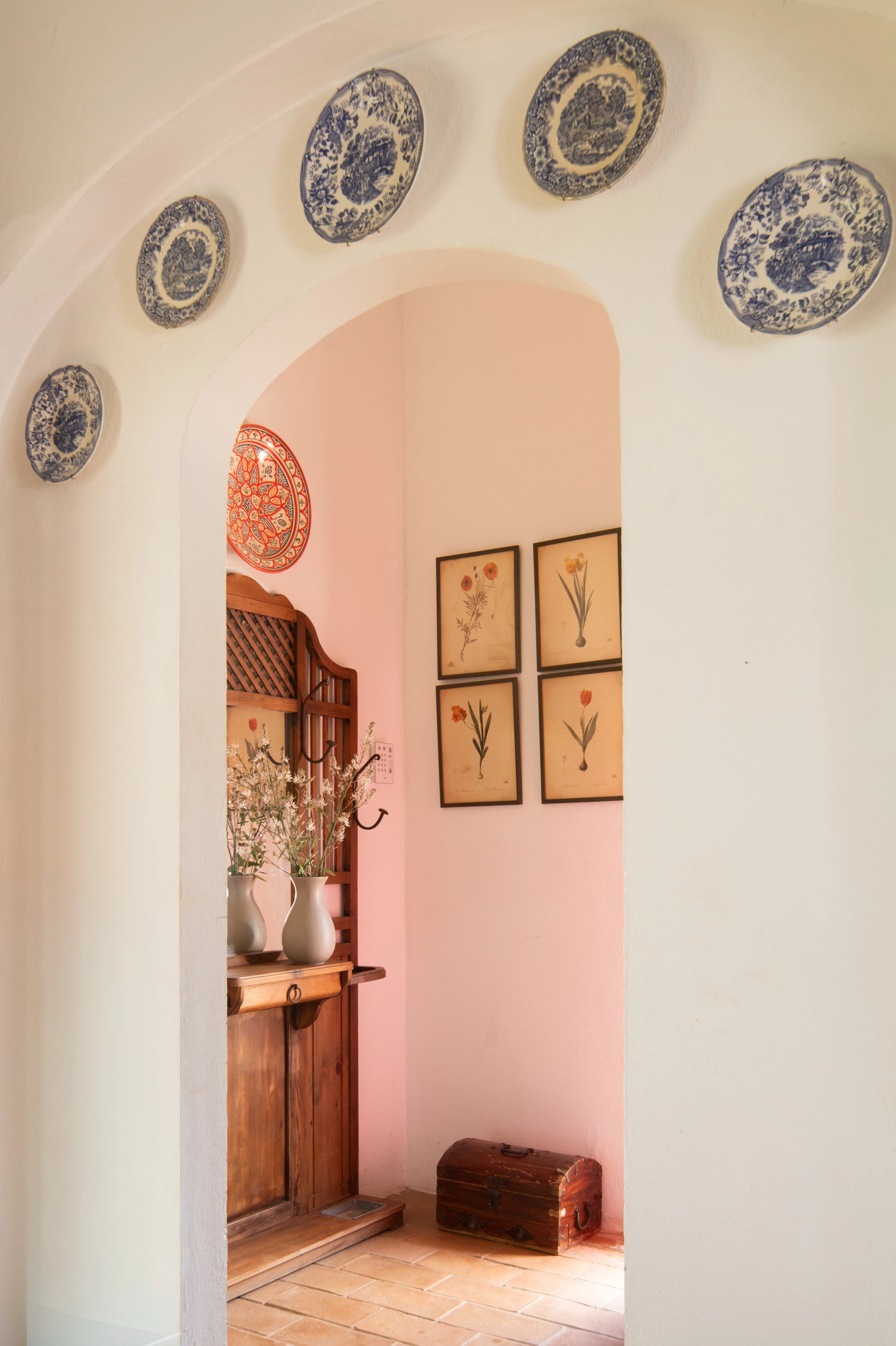Archway entrance to hotel room with floral prints and decorative plates. Epoca Suites: Corporativa.