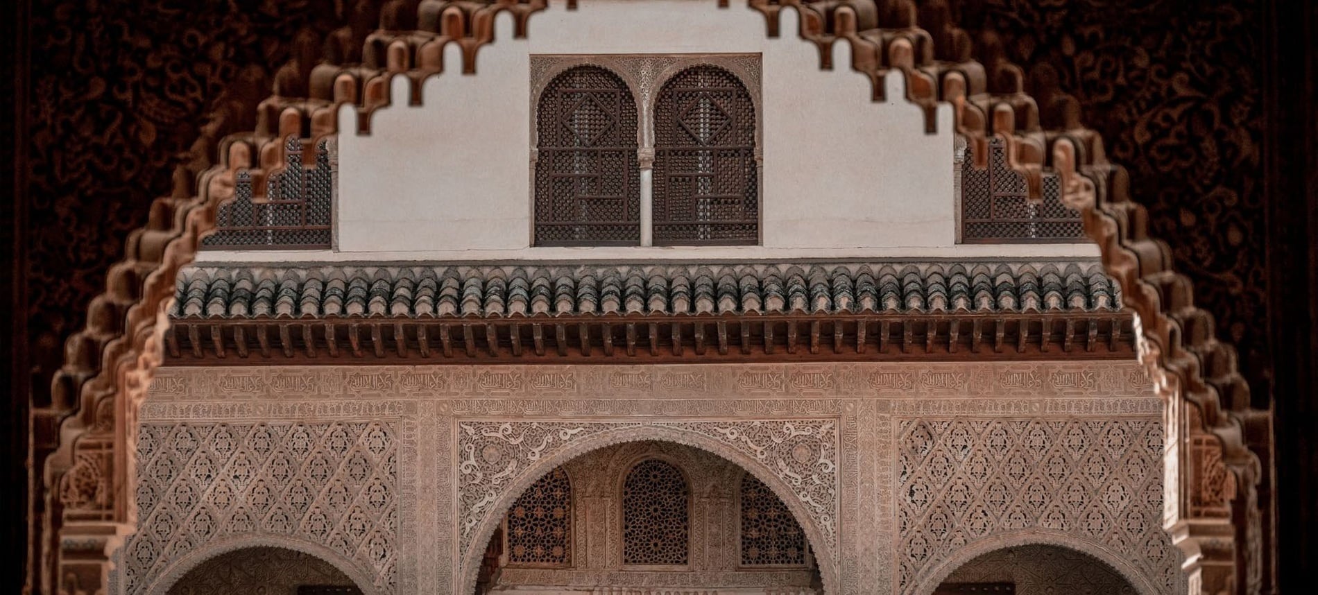 Detallada vista frontal de intrincada arquitectura morisca adornada con arcos, celosías y motivos caligráficos.
