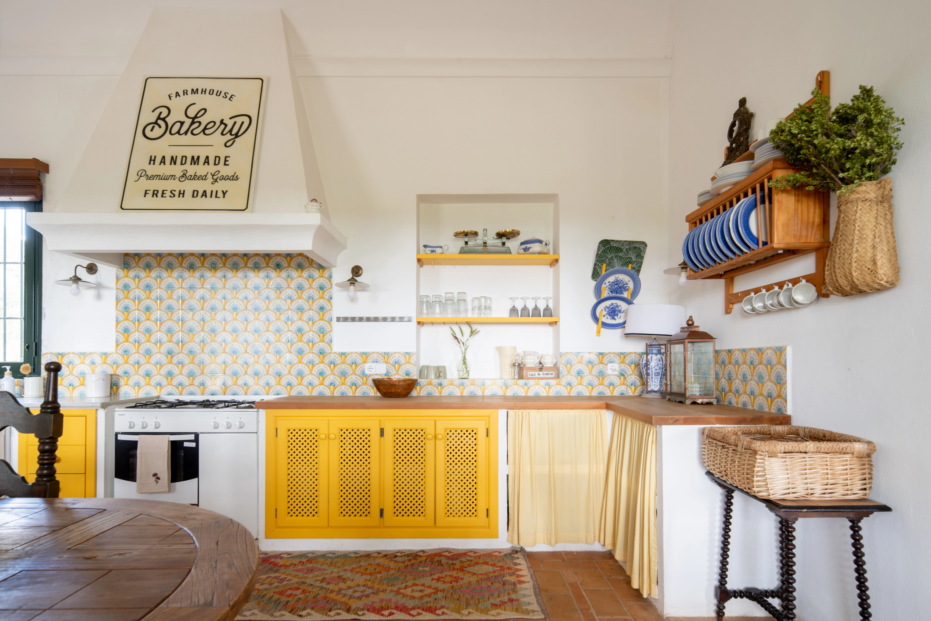 Rustic kitchen with yellow cabinets, traditional tiles, and a 'Farmhouse Bakery' sign Epoca Suites: Corporativa.