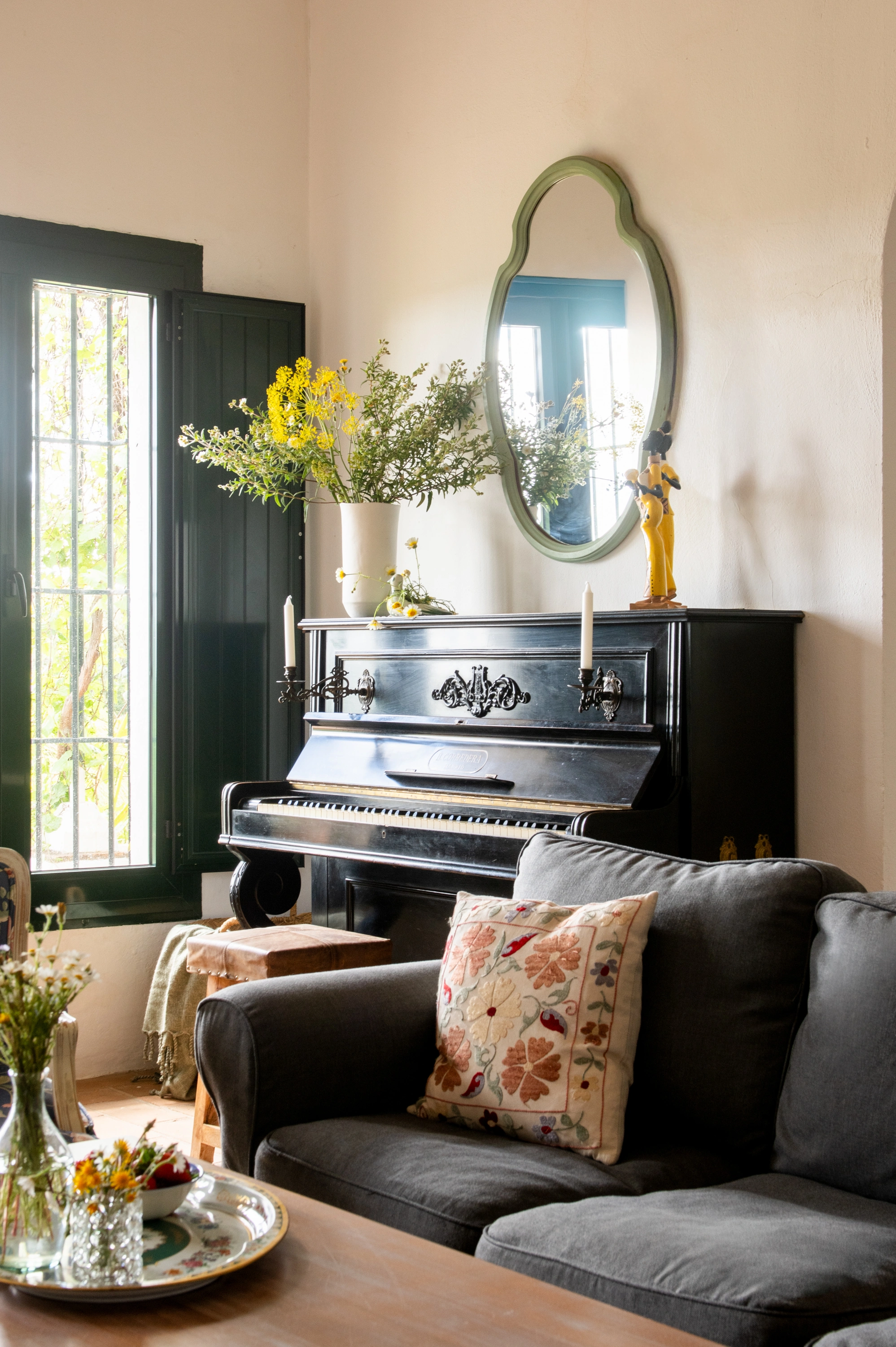 Elegant piano and sofa with decorative pillow in a bright room, perfect for Epoca Suites: Corporativa experiences.
