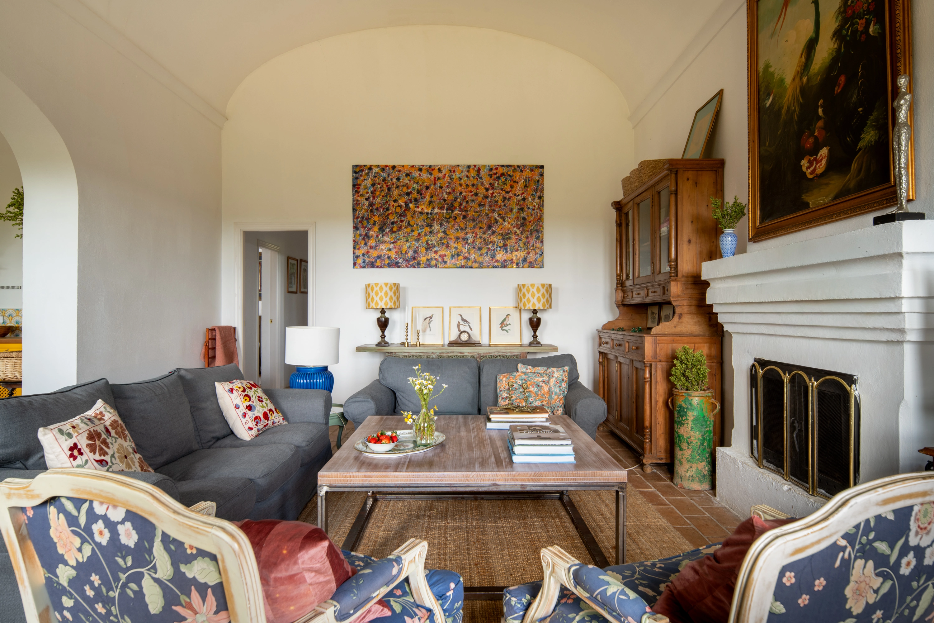Elegant living room with couches, fireplace, artwork, and rustic furniture. Epoca Suites: Corporativa for a luxurious stay.