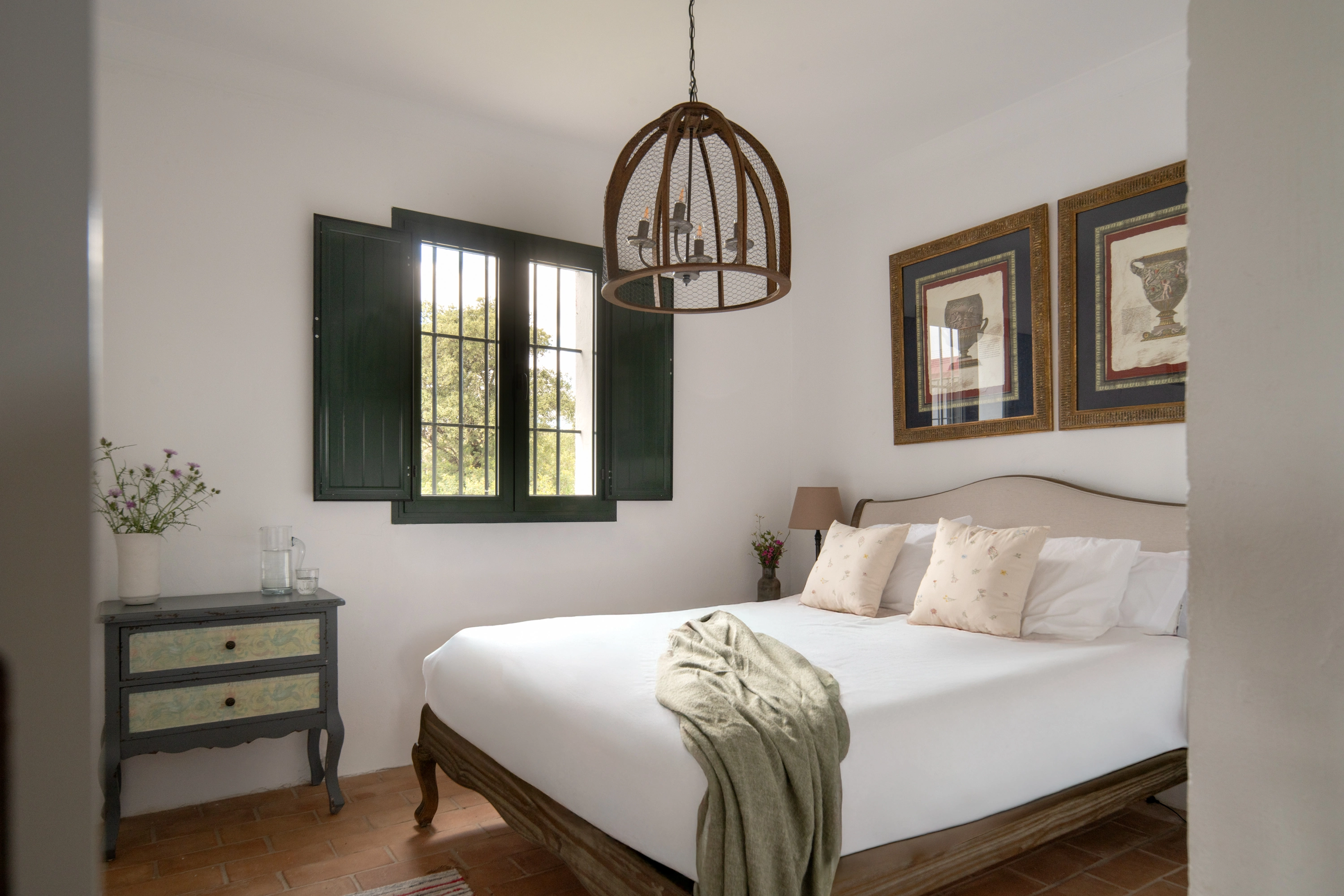 Charming hotel bedroom with a white bed, two decorative pillows, and a cozy throw. Epoca Suites: Corporativa