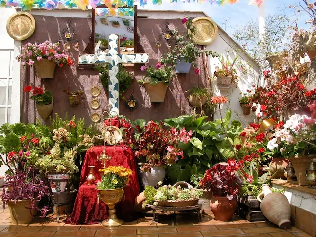 Fachada de Epoca Suites: Corporativa adornada con flores vibrantes y cruz decorativa.