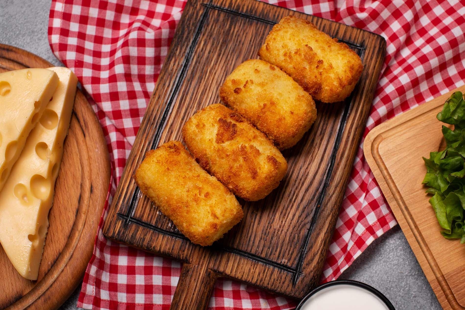 una tabla de cortar de madera llena de croquetas de queso