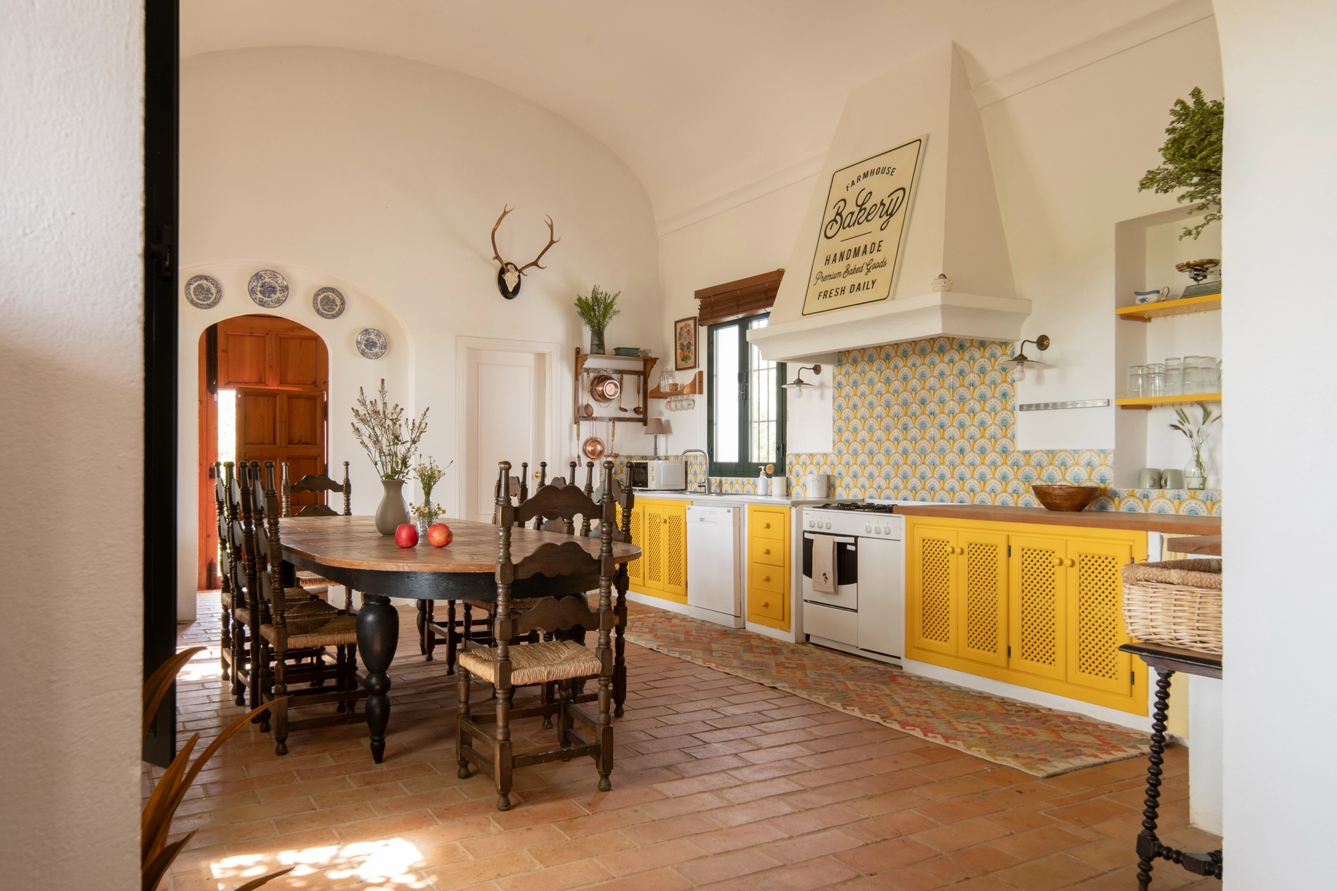 Farmhouse kitchen with dining table, yellow cabinets, and vintage decor. Villa Lavender | Época Suites | Official Web