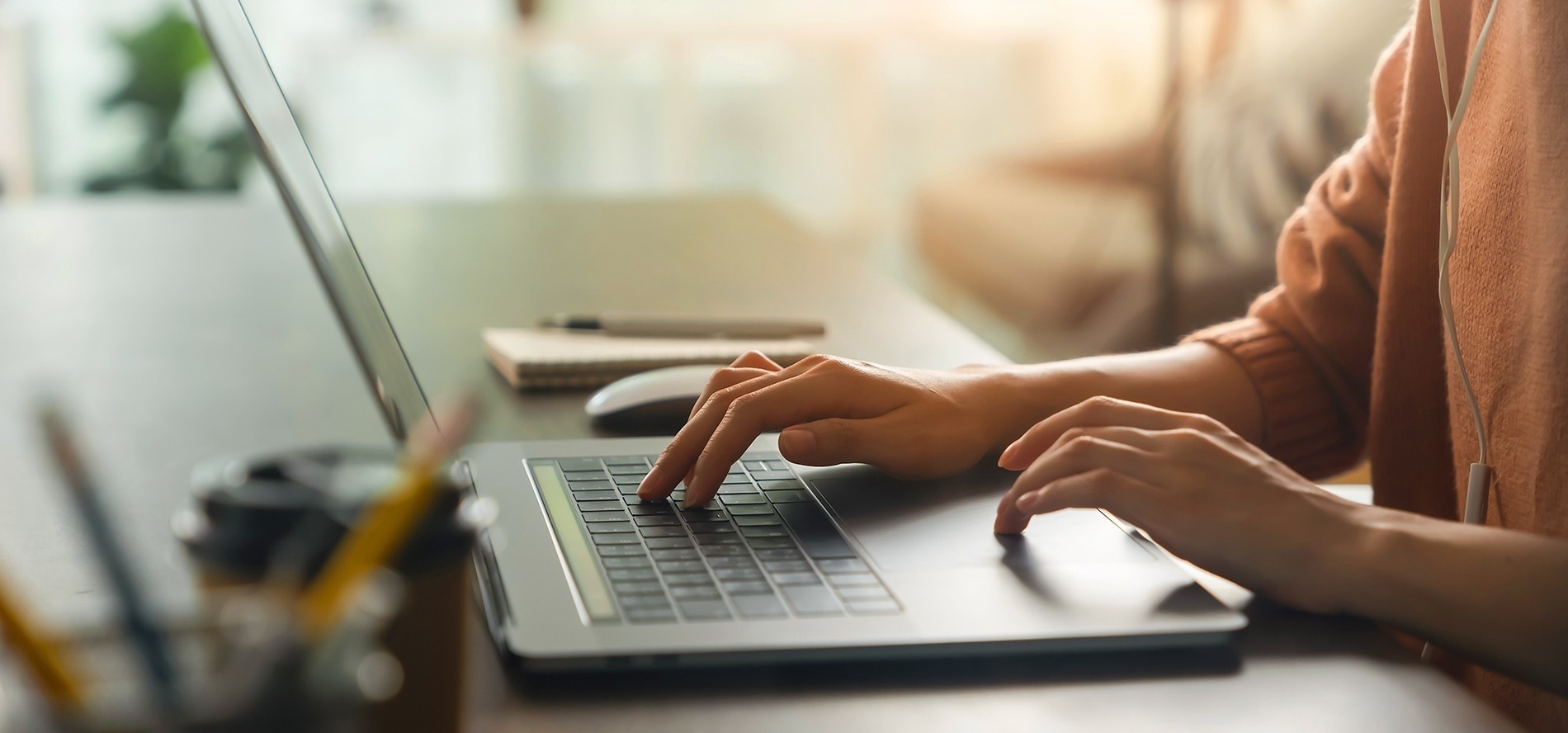 una mujer con un anillo en el dedo izquierdo está escribiendo en una computadora portátil