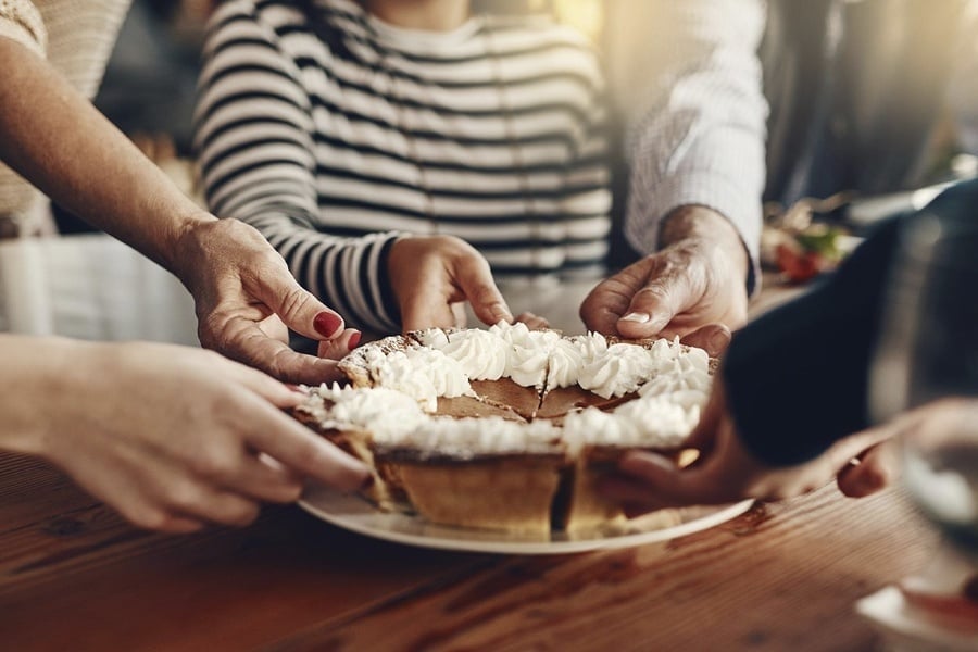 a group of people holding a pie with whipped cream on top