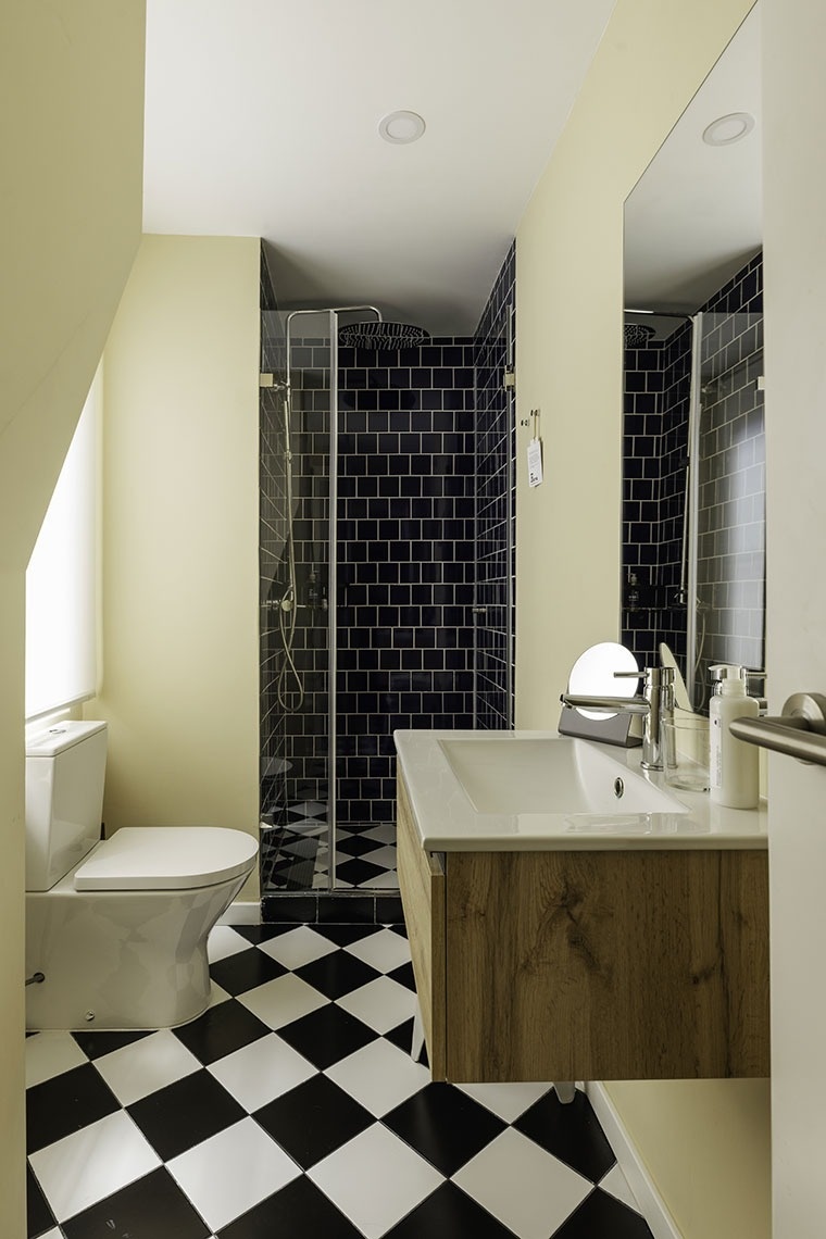 Modern bathroom with checkerboard floor and shower at Esqina Apartments.