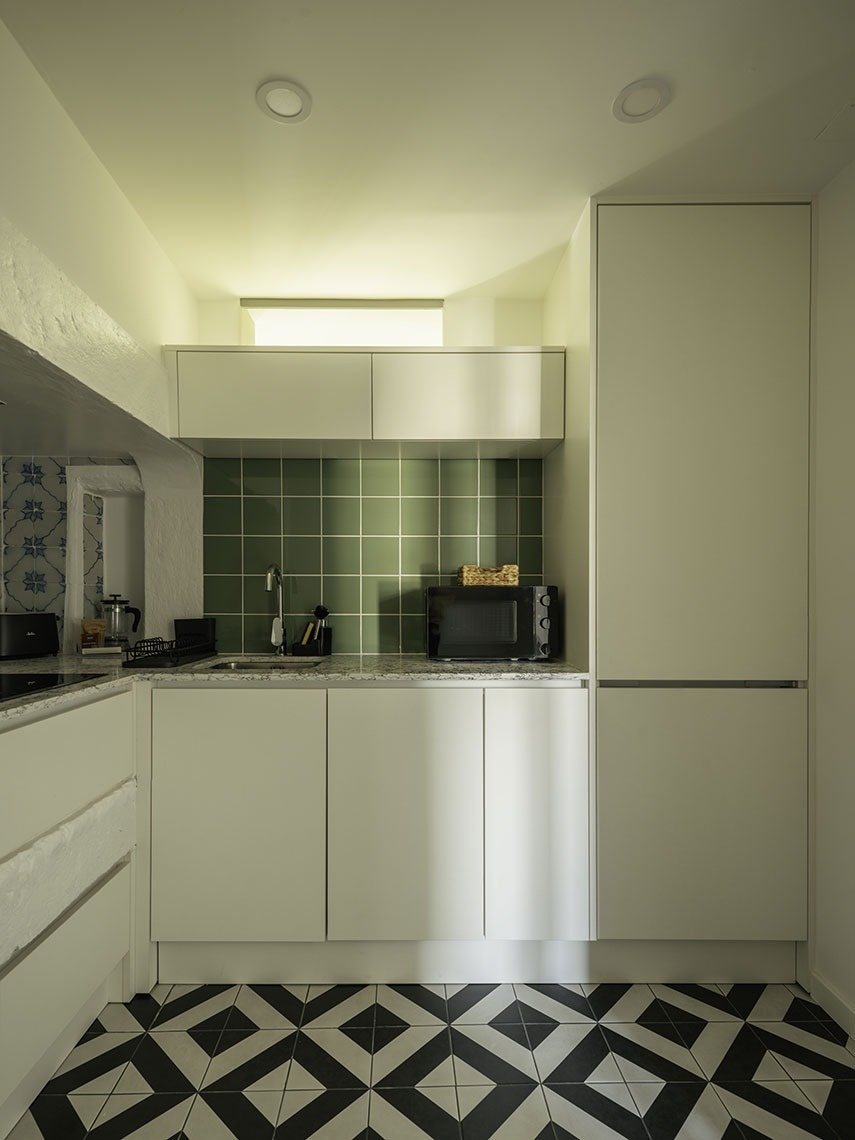 Modern kitchen at Esqina Apartments featuring green tiles and geometric flooring.