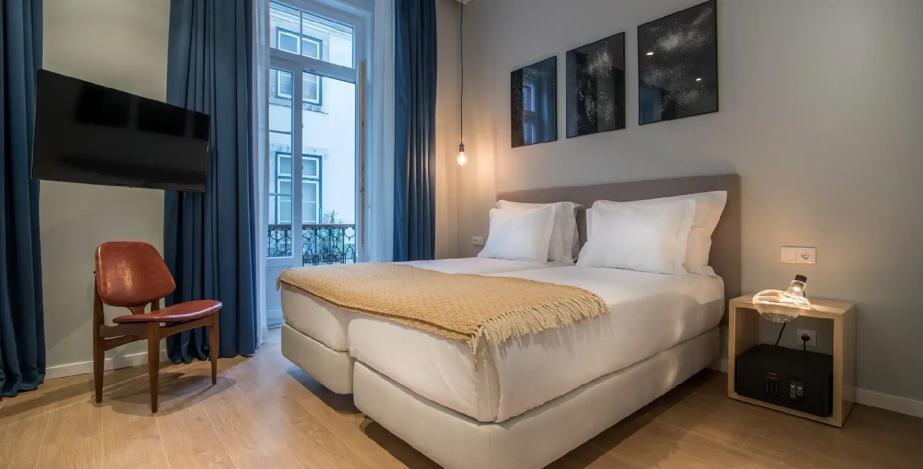 Stylish hotel room at Esqina Apartments with twin beds, TV and window view.