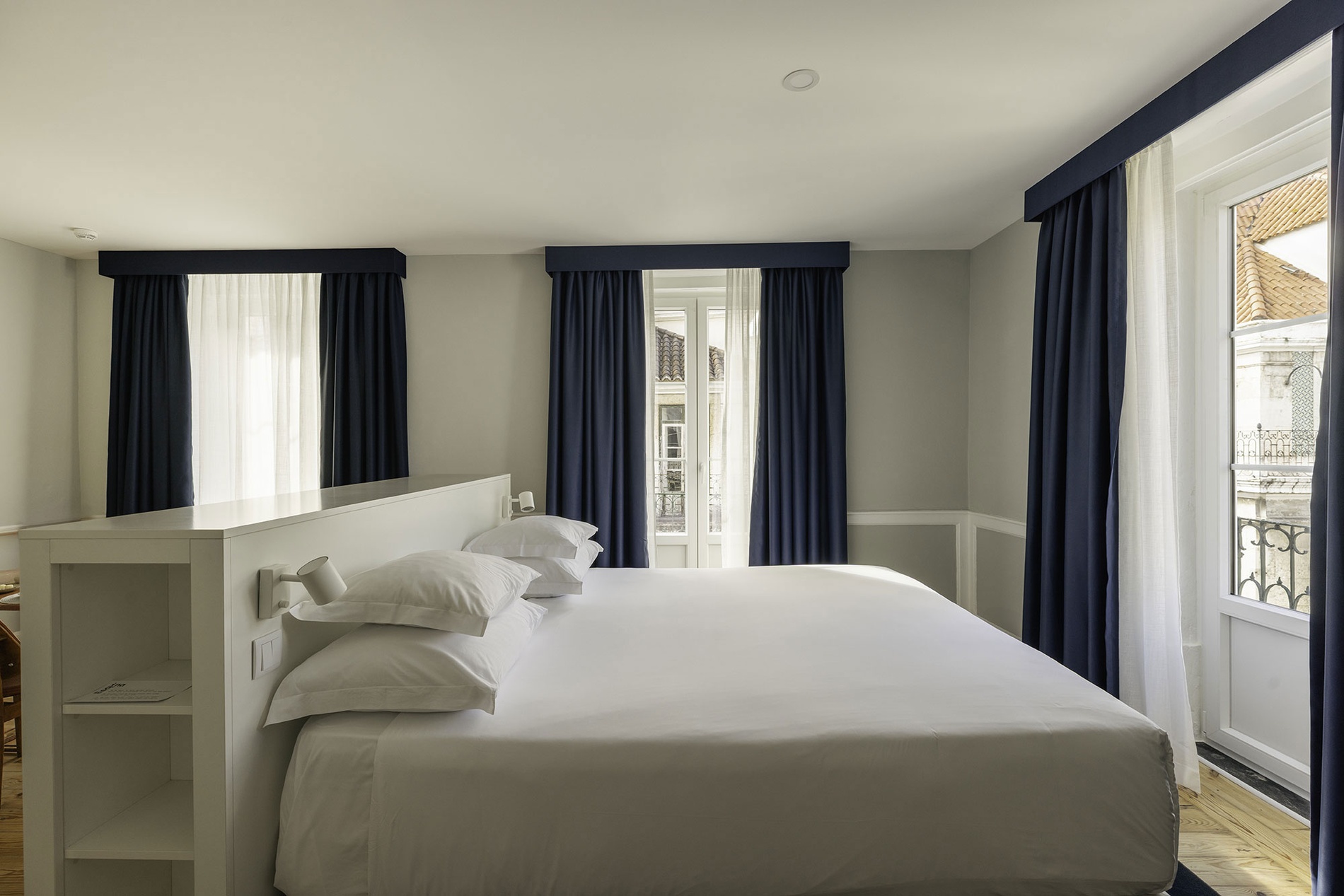 Room at Esqina Apartments: double bed, blue curtains, and exterior view.