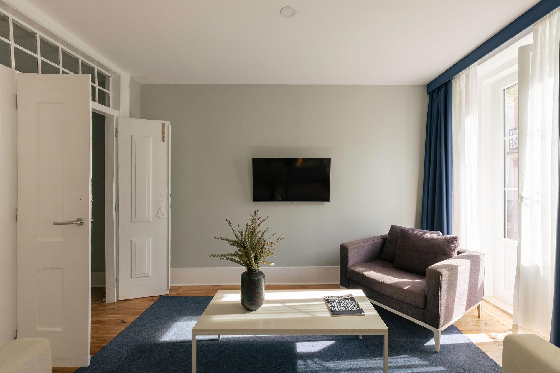 Cozy living room at Esqina Apartments featuring a sofa and TV, perfect for relaxation.