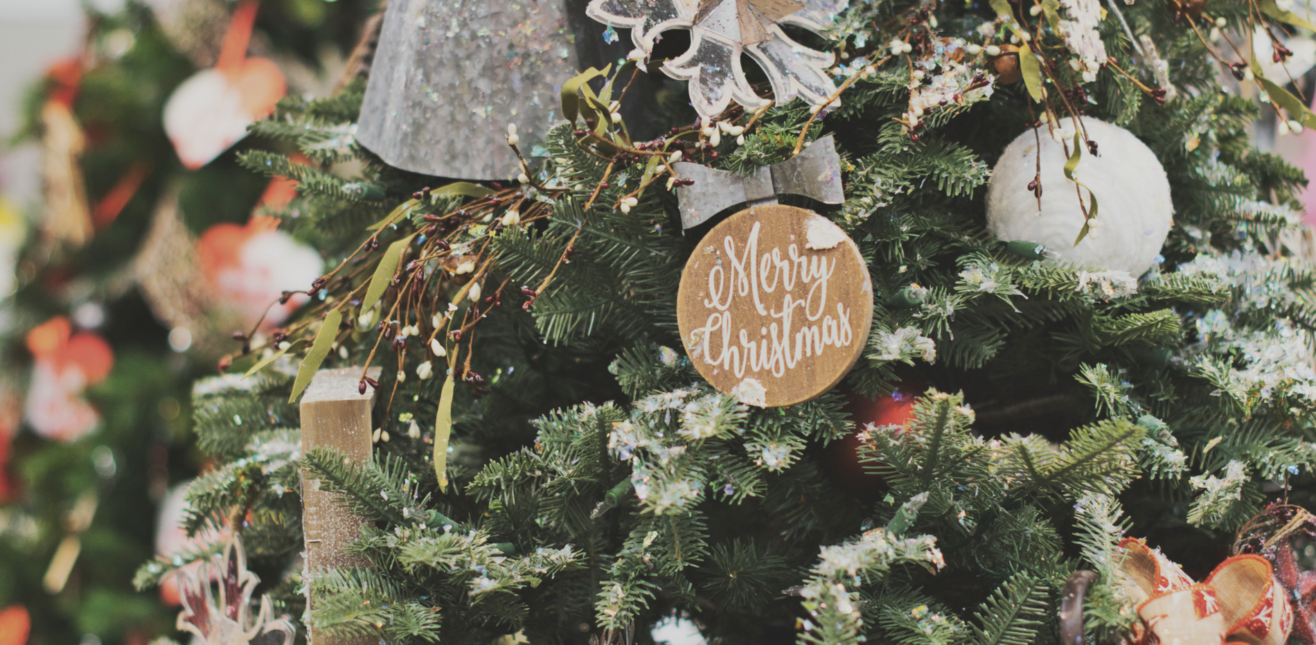 uma árvore de natal com uma placa de madeira que diz feliz natal