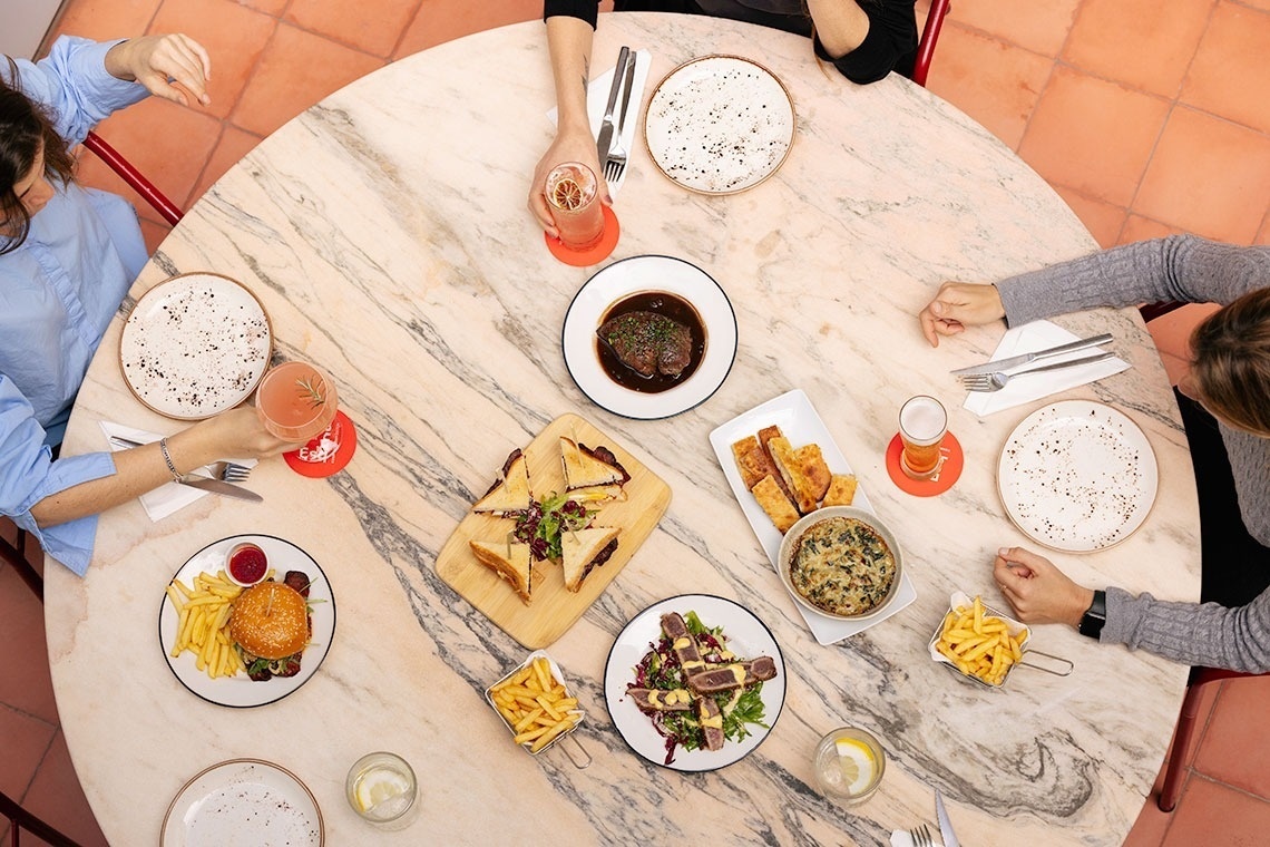 a group of people are sitting at a table with plates of food