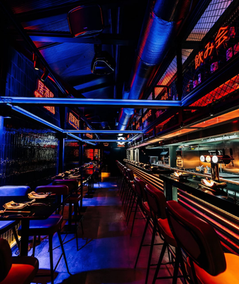 un grupo de personas están sentadas en mesas bajo una carpa decorada con guirnaldas de colores .