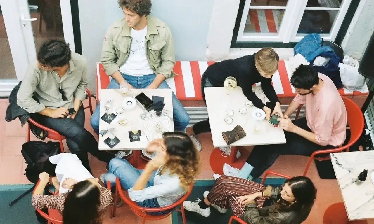 a group of people sitting at tables with a man wearing a white shirt that says ' i love you ' on it