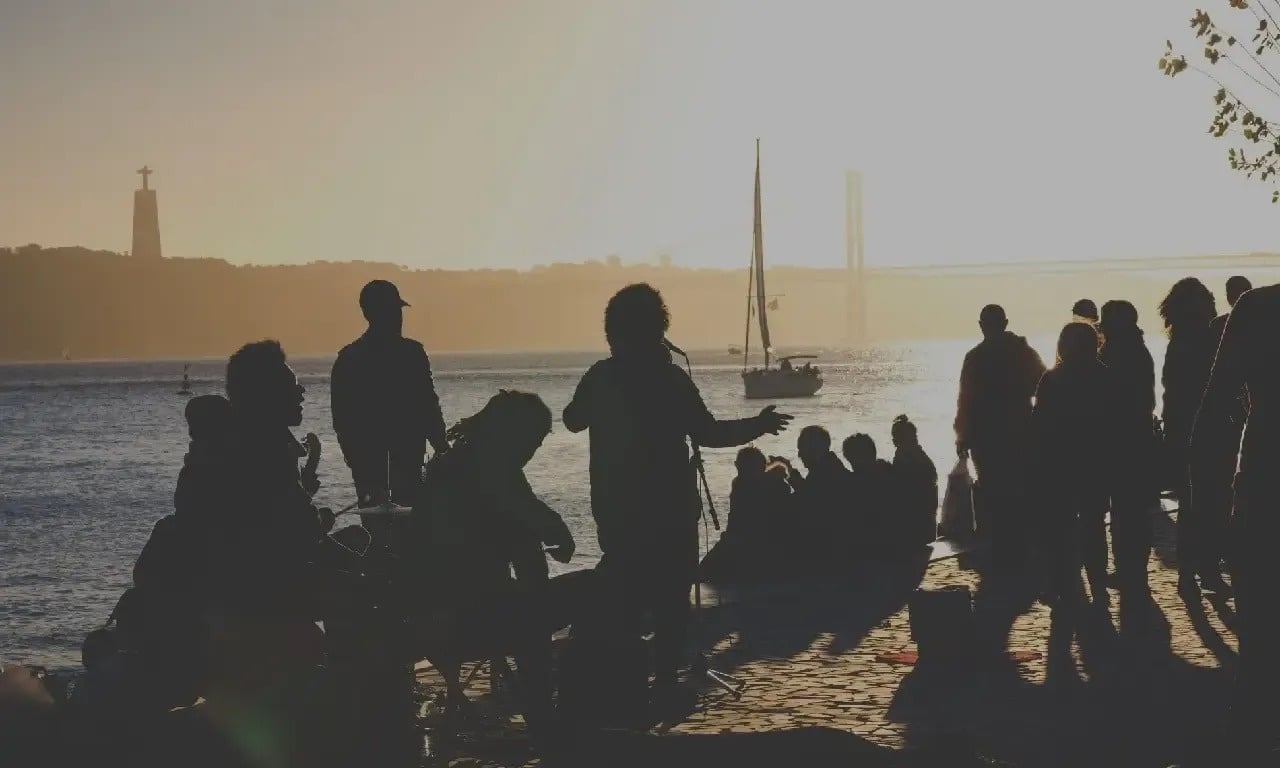 un grupo de personas se reúnen en la orilla del océano al atardecer