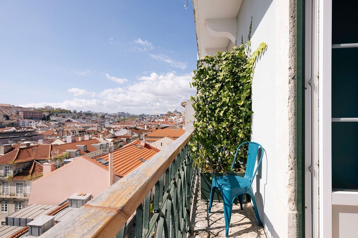 uma cadeira azul está em uma varanda com vista para a cidade