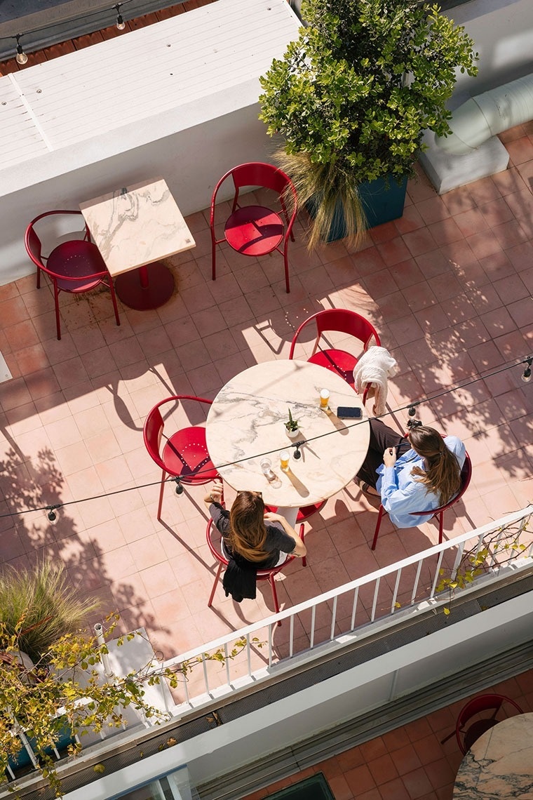 duas mulheres estão sentadas em uma mesa redonda com cadeiras vermelhas