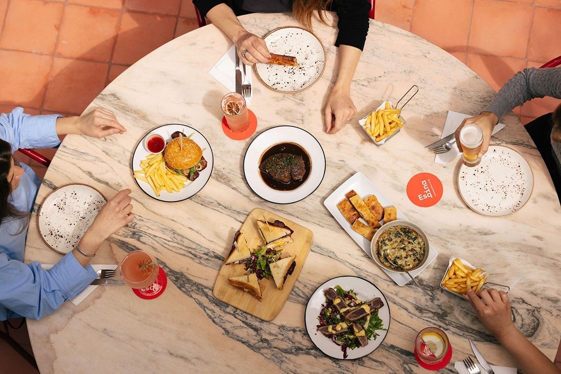 um grupo de pessoas está sentada em uma mesa com pratos de comida
