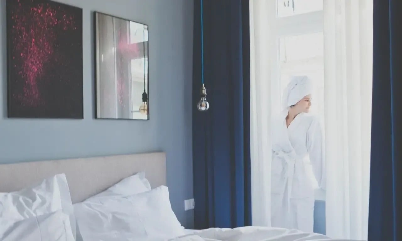 a woman in a bathrobe is looking out a window