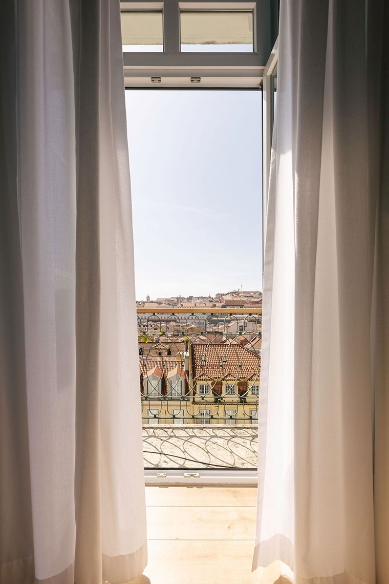 uma janela aberta com cortinas brancas e uma vista da cidade