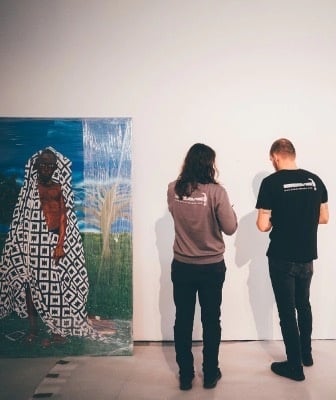 a man and a woman are looking at a painting on a wall