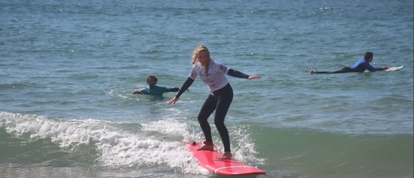a girl is riding a wave on a red surfboard