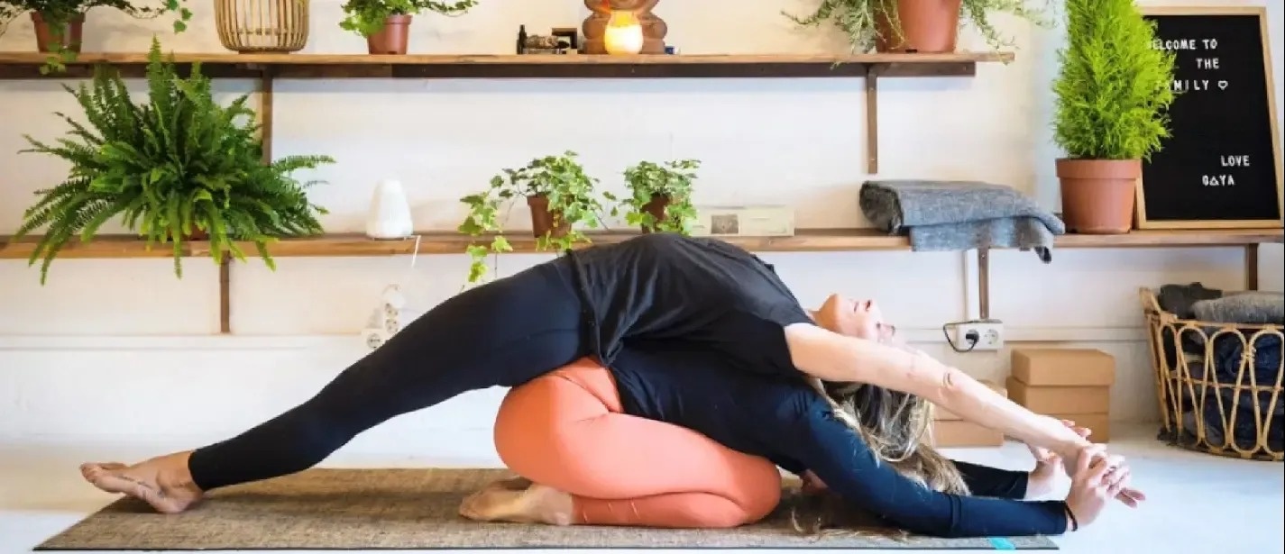 two women are doing yoga in front of a sign that says 