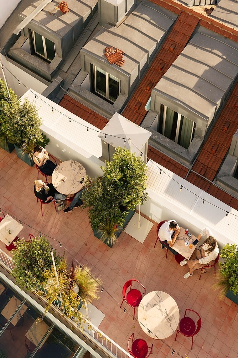 an aerial view of people sitting at tables on a rooftop