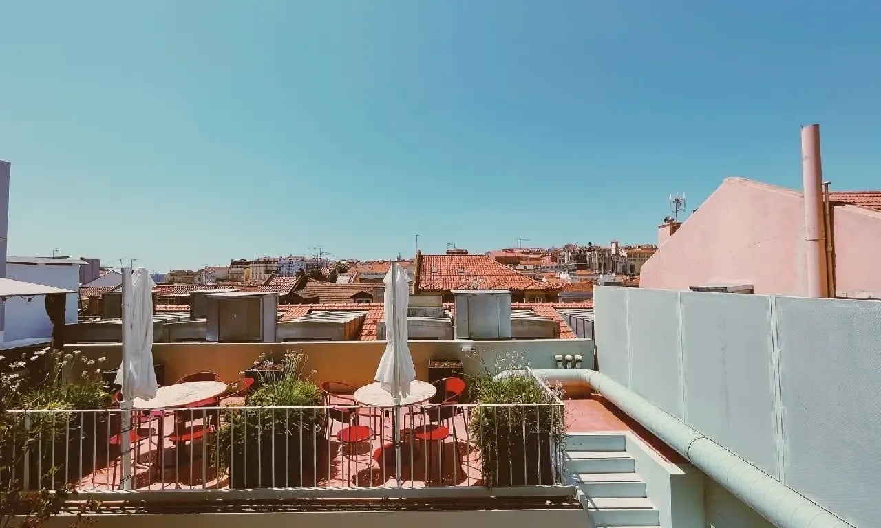 a balcony with tables and chairs and umbrellas overlooking a city