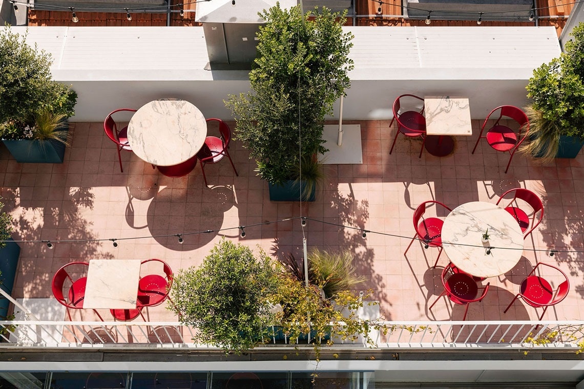 uma vista aérea de uma varanda com mesas e cadeiras vermelhas