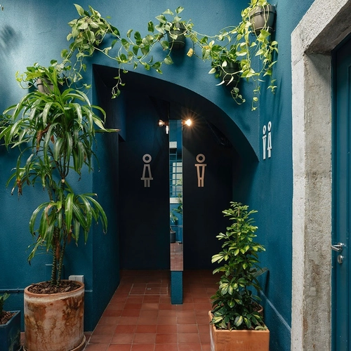 a hallway with plants and a sign that says ' unisex ' on it