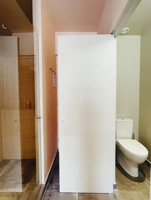 un baño con una puerta blanca y un inodoro