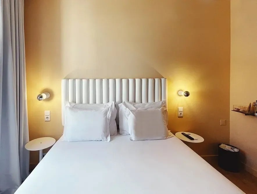 a bed with white sheets and pillows in a hotel room