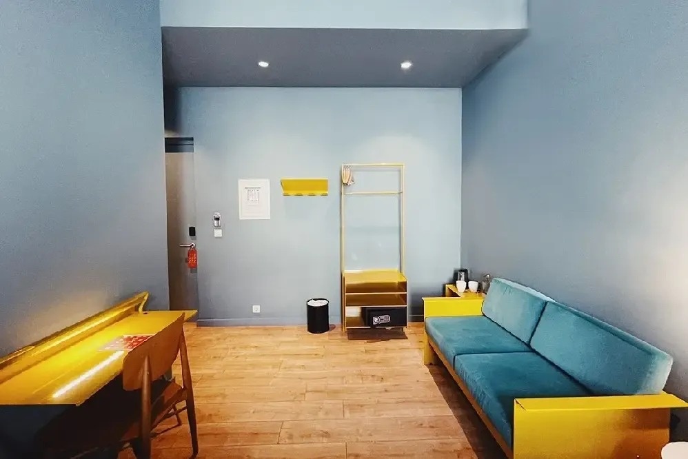 una habitación con un sofá azul y un escritorio amarillo