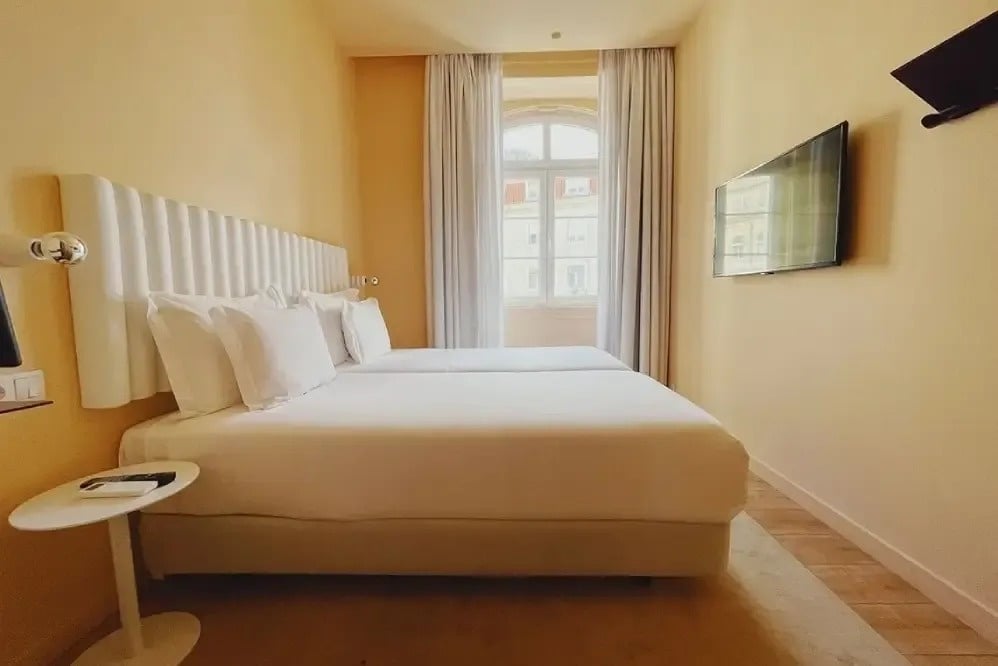 una habitación con dos camas y una televisión en la pared