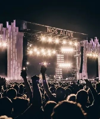 una gran multitud de personas está parada frente a un escenario en un festival de música .