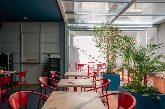 a restaurant with red chairs and tables has a sign that says ' coca cola ' on it
