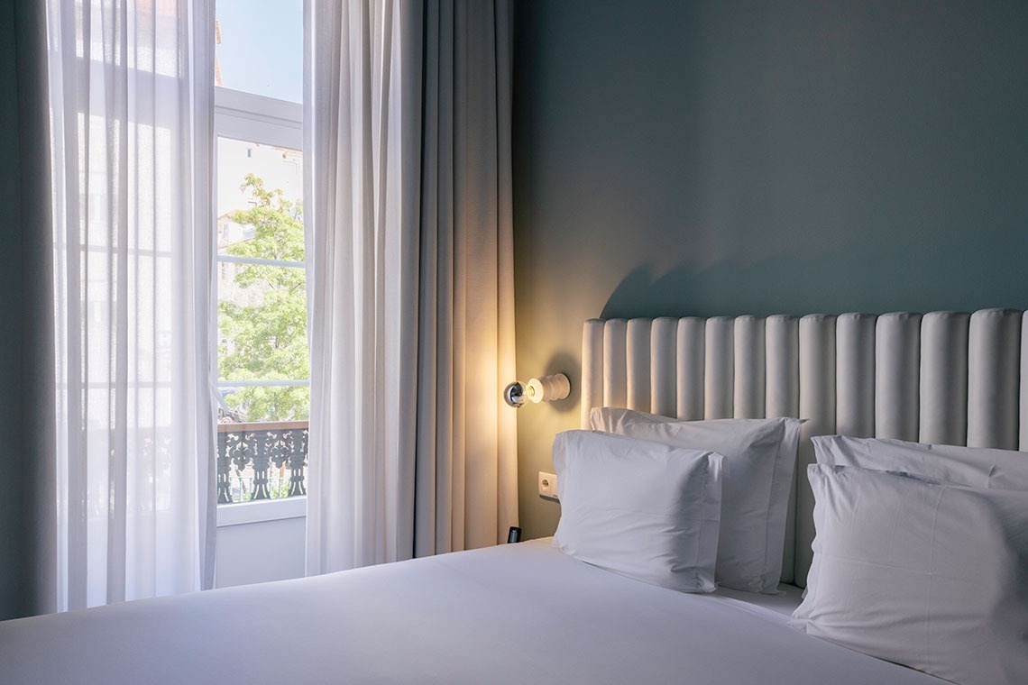 a bedroom with a bed and a window with white curtains