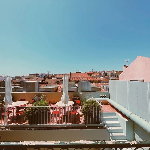 a balcony with tables and chairs and umbrellas on it