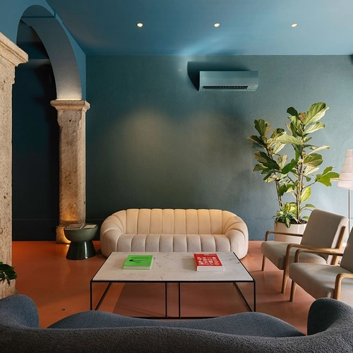 a living room with a couch a table and chairs and a plant
