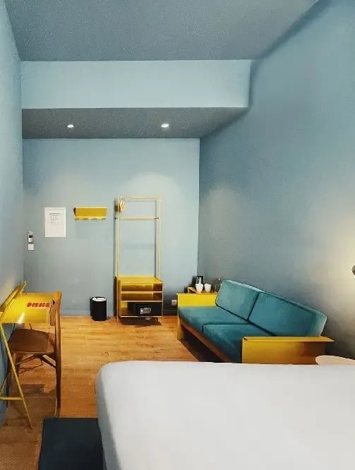 un dormitorio con paredes azules , un sofá azul , un escritorio y una cama .