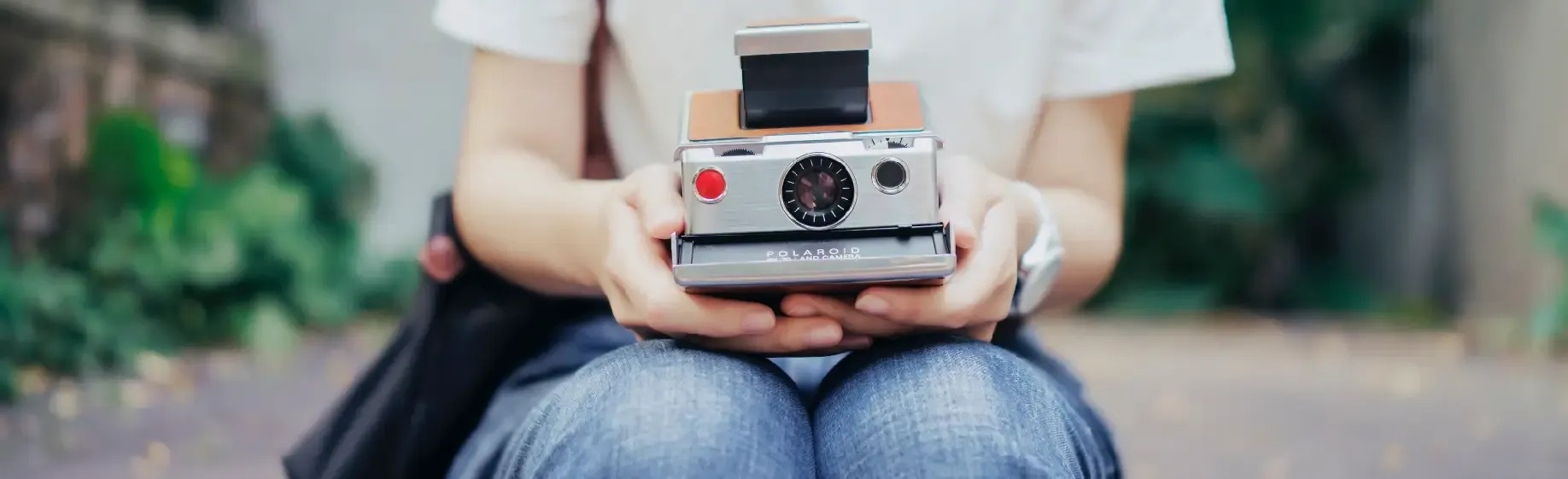 una persona sostiene una cámara polaroid en sus manos .