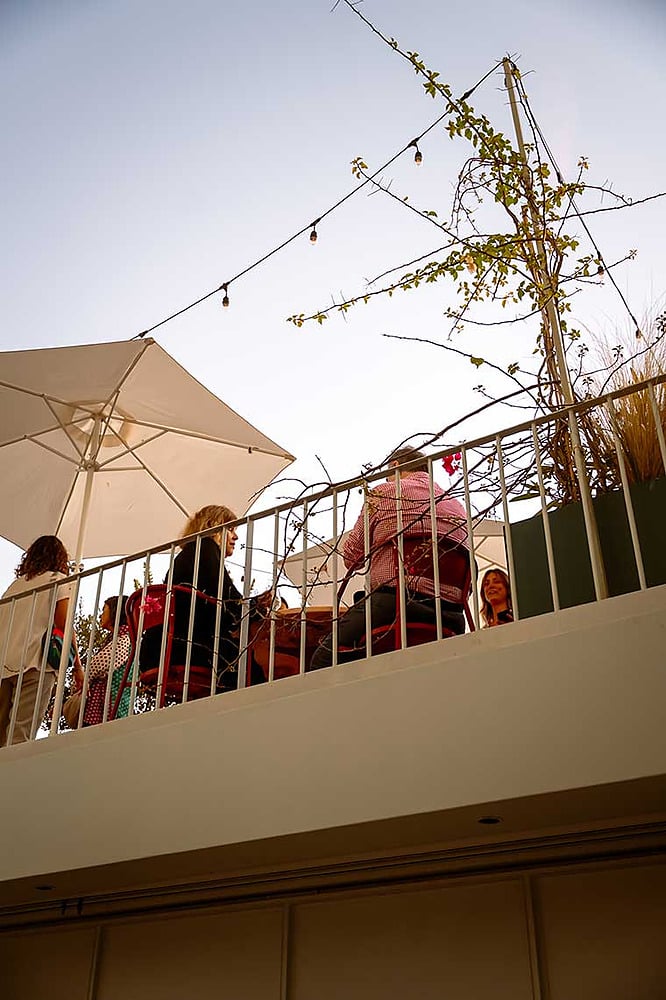 Terraza de hotel con Esqina: Cosmopolitan, sombrillas y luces colgantes.