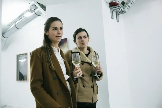 two women standing next to each other holding wine glasses